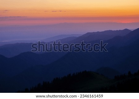 Silhouettes of mountain ranges in the morning haze. Blue hour                                Royalty-Free Stock Photo #2346161459