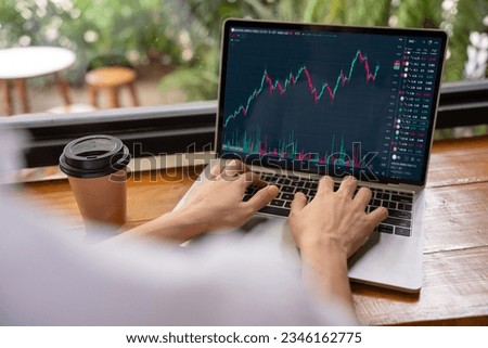 Hand of woman in coffee shop using laptop check, look graph on monitor screen for buy or sell on stock exchange market. Investment concept. Wireless or 5G technology. Royalty-Free Stock Photo #2346162775