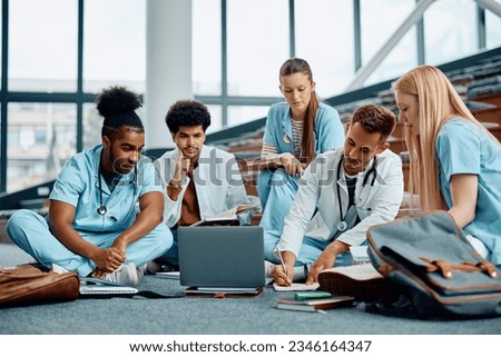 Multiracial group of medical students using computer while studying in lecture hall. 