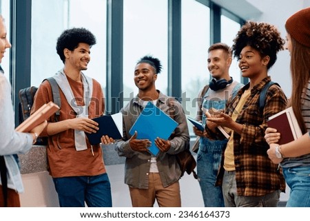 Happy African American college student talking to her classmates in a hallway. Royalty-Free Stock Photo #2346164373