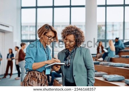 Happy businesswomen using mobile phone after attending an education event at conference hall.  Royalty-Free Stock Photo #2346168357