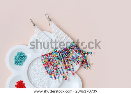 Beaded earrings and bead trays. Different colored seed beads for needlework and beading. Creativity and  hobby concept Royalty-Free Stock Photo #2346170739