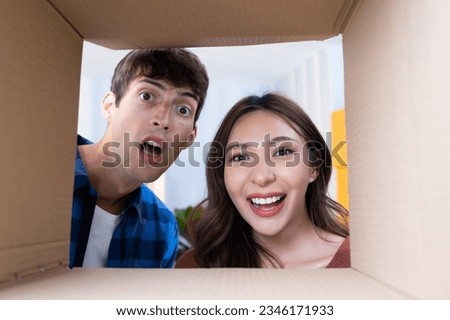 Young couple open up gift box and reach their hand to taking gift outside of the parcel box. Happiness and surprise moment with new gift or new purchase deliver and unboxing gift. Royalty-Free Stock Photo #2346171933