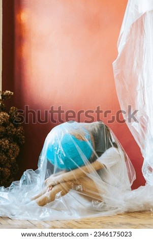 environmental disaster, the problem of plastic pollution of the entire earth and the oceans, a teenage girl with a globe in her hands is wrapped in a polyethylene film