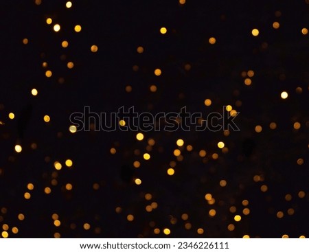 Glowing Particles Stock Image In Black Background, Festive abstract Christmas texture, golden bokeh particles and highlights on dark background. High quality photo