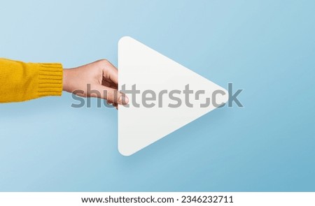 Hand holding white media player button icon on yellow background Royalty-Free Stock Photo #2346232711