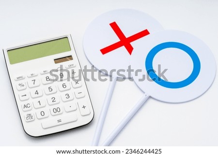 A calculator and a plate of circles and crosses. white background.