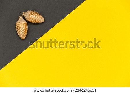 Christmas gold pinecones on grey and yellow background. Christmas, New Year geometric background. Flat lay, copy space.