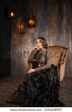 A stylish lady in an elegant Victorian-style suit, sitting in an armchair. costume with steampunk elements, Royalty-Free Stock Photo #2346248957