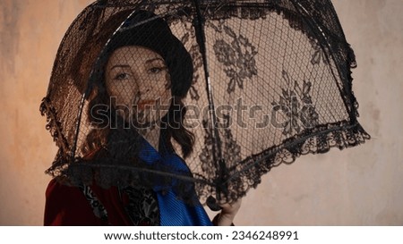 stylish lady in a burgundy old - fashioned suit with a hat and a lace umbrella . Brunette in a retro style suit Royalty-Free Stock Photo #2346248991