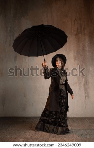A stylish lady in an elegant Victorian-style suit, in a hat with an umbrella in her hands, is ready to take off like Mary Poppins Royalty-Free Stock Photo #2346249009