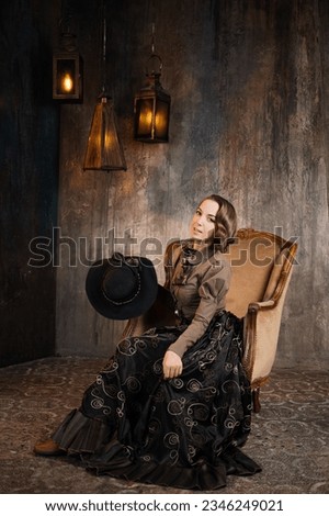 A stylish lady in an elegant Victorian-style suit, sitting in an armchair. costume with steampunk elements, Royalty-Free Stock Photo #2346249021