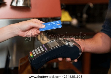 Close-up customer hand using credit card with data reading system to pay with a credit card reader for coffee and bakery Minimize contact and no cash payments Not enough cash. In cafe while traveling