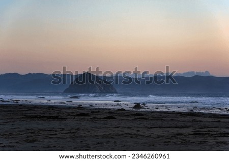 A beautiful sunset over a beach in California. The sky is ablaze with color, from fiery oranges and reds to soft pinks and purples. The beach is empty with footprints in the sand.