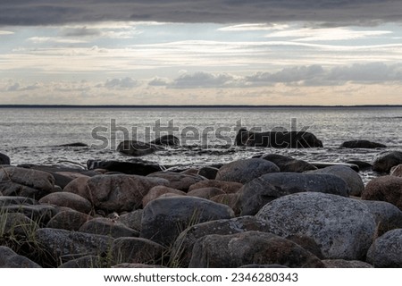 Sunset view from parispea beach in Lahemaa national park, Estonia. Image shows sunset with partial clouds and a calm sea washing over the rocky beach. August 2023