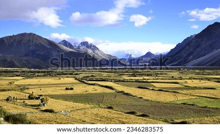 Capturing the enchanting allure of Tibet's untouched beauty, this image portrays a mesmerizing vista. The golden sun dips below the towering peaks, casting a warm, ethereal glow across the tranquil la Royalty-Free Stock Photo #2346283575