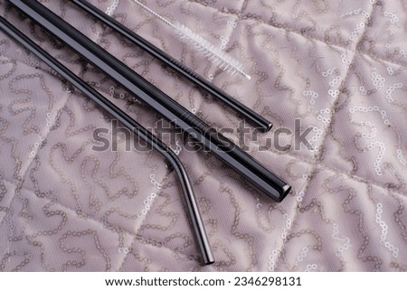 flat lay reusable sets of black stainless steel straws on textured grey fabric, eco friendly lifestyle