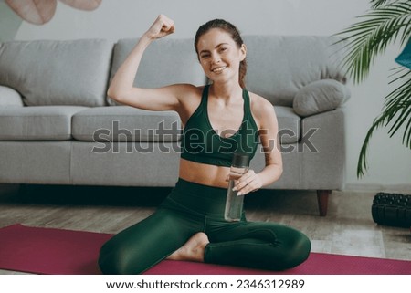 Full body happy young strong sporty athletic fitness trainer instructor woman wear green tracksuit drink water show muscles training do exercises at home gym indoor Workout sport motivation concept Royalty-Free Stock Photo #2346312989