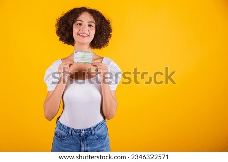 Caucasian model, in white shirt and blue jeans, holding voting card, voter registration card. translation in English (voter card)