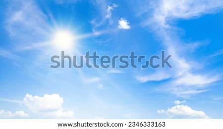 The bright sun, blue sky and light clouds. Wide photo.