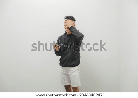 a young man wearing a black jacket on a white background is using his smartphone