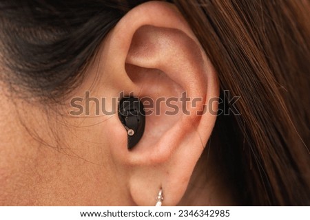 Young woman with a hearing aid hidden in her ear on a light background  Royalty-Free Stock Photo #2346342985
