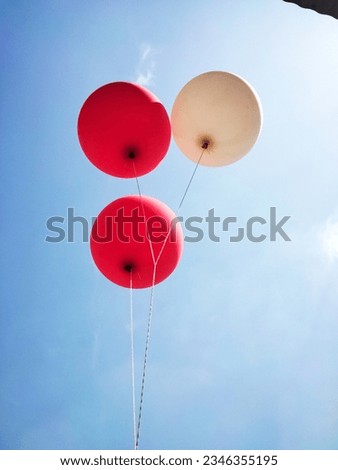 an image of a balloon red and white in the air against a blue sky on a sunny day