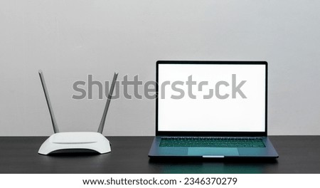 Laptop with blank screen and wireless internet router on the table. Internet connection.