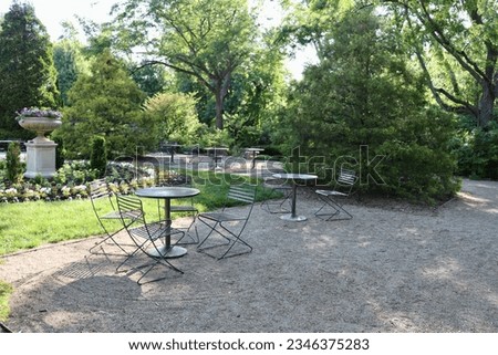 The empty tables and chairs in the garden at the park.