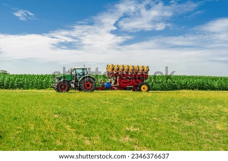 Agricultural machinery drives across field. Big tractor. SIder view. White cumulus clouds background Royalty-Free Stock Photo #2346376637