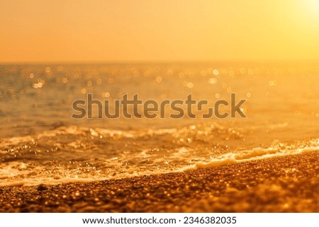 Abstract nature summer ocean sunset sea background. Small waves on water surface in motion blur with bokeh lights from sunrise. Holiday, vacation and recreational background concept