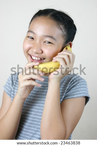 Pretty girl holding banana as a phone.