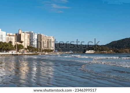 City of Santos, Brazil. Santos beach during high tide in Ponta da Praia neighborhood. In the background, the fortress of Barra at the entrance to the port channel.