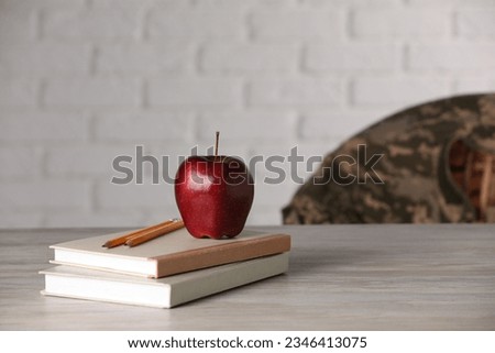 Notebooks, apple and pencils on wooden table, space for text. Military education