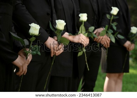 People in black clothes with white rose flowers outdoors, closeup. Funeral ceremony Royalty-Free Stock Photo #2346413087