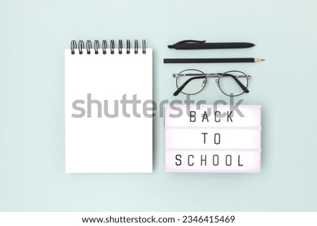 Back to school. Lightbox with letters and stationery on a blue background. Empty notepad mockup.