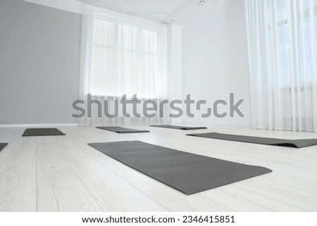 Spacious yoga studio with exercise mats, low angle view. Space for text