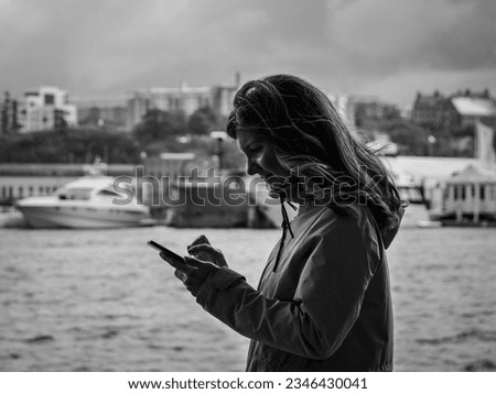 Side view of woman using mobile phone while standing by river in city