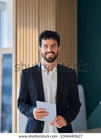Smiling professional young latin business man company employee, male corporate manager, businessman office worker looking at camera holding digital tablet standing in office, vertical portrait. Royalty-Free Stock Photo #2346440627