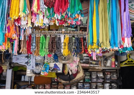 Sewing equipment store, display of zippers with various colors, threads, scissors, sewing kit.  Royalty-Free Stock Photo #2346443517