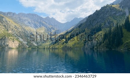Amazing view of the green wooded hills, mountains and rocks at the beautiful lake Sary Chelek. The State Biosphere Reserve is a specially protected natural territory of Kyrgyzstan. Royalty-Free Stock Photo #2346463729