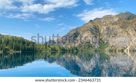 Sary Chelek mountain Lake in Kyrgyzstan. Summer landscape. Mountains, rocks and hills covered with green forests. The State Biosphere Reserve is a specially protected natural territory of Kyrgyzstan. Royalty-Free Stock Photo #2346463731