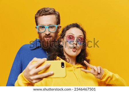 Woman and man funny couple with phones hand social networking and communication crooked do selfies smile fun, on yellow background. The concept of real family relationships, freelancers, work online.