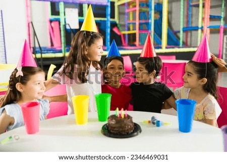 Excited group of kids laughing and having fun while celebrating a friend’s birthday party in the indoor playground Royalty-Free Stock Photo #2346469031