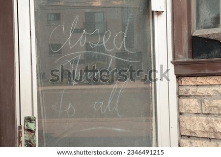 chalk writing closed thanks to all on chalkboard inside down window storefront with brick and window next to it