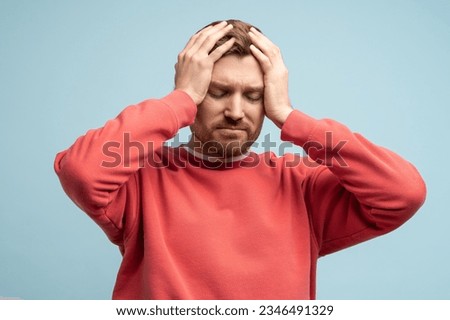Portrait of sad man having life troubles holding head with suffering face on studio blue background. Frustrated, confused male with headache, life problems, midlife crisis. Stress, panic, desperation. Royalty-Free Stock Photo #2346491329