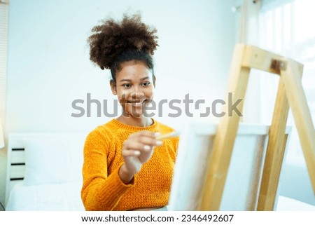 Happy cheerful American - African black ethnicity pregnant woman enjoy drawing and painting a water color on canvas in bedroom, hobby and activity for pregnant woman.