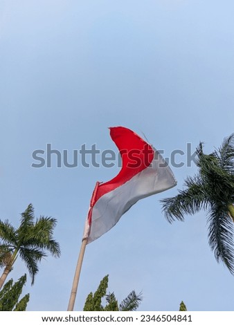 A photo of the Indonesian national flag flying under a clear blue sky