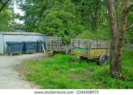 Old passenger trailers are parked in the yard on a summer day