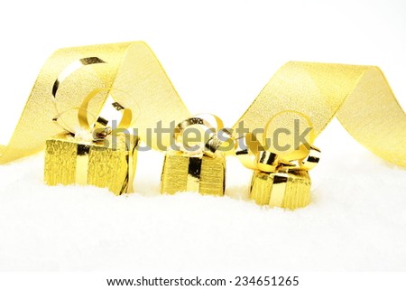 Decoration of golden christmas gifts with ribbon on snow on white background